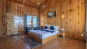 A wooden-paneled bedroom with a bed, bedside table, and a window with curtains.