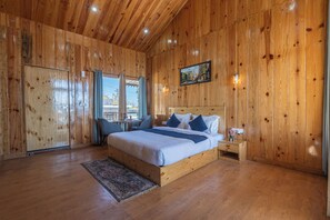 A wooden-paneled bedroom with a bed, bedside table, and a window with curtains.