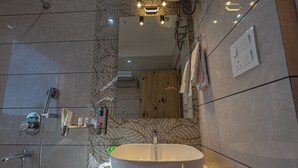 A modern bathroom with a large oval sink, a glass shower enclosure, and a wooden panel wall.