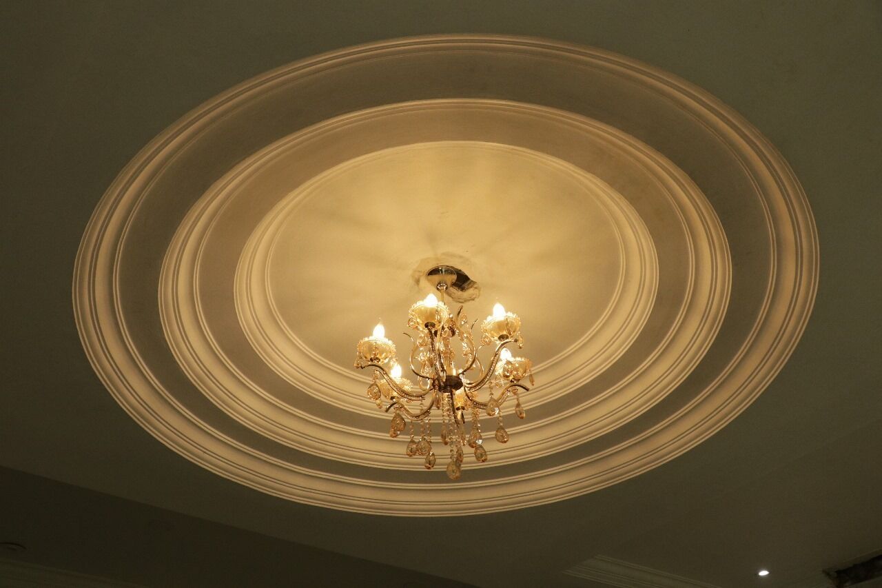 A chandelier with multiple arms and candle-like lights, centered in a circular ceiling design.