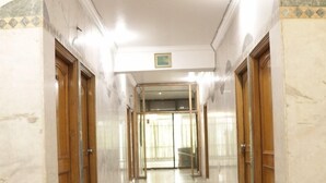 A marble-floored corridor with wooden doors and a glass entrance. - Hotel Royal Palace Jalandhar (Jalandhar)