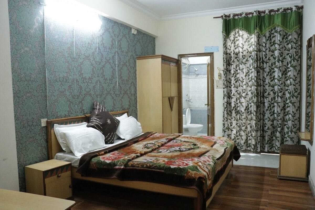 Une chambre à coucher comprenant un lit, une armoire, une table de chevet et une salle de bain avec des toilettes et une douche.
