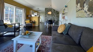 A modern living room with a sofa, armchairs, a coffee table, and a dining area with chairs and a table. - Tranquil Lakeside Stay for 4 Guests (Sint Nicolaasga)