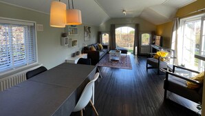 A modern living room with a dining area, large windows, and a view of the outdoors. - Tranquil Lakeside Stay for 4 Guests (Sint Nicolaasga)