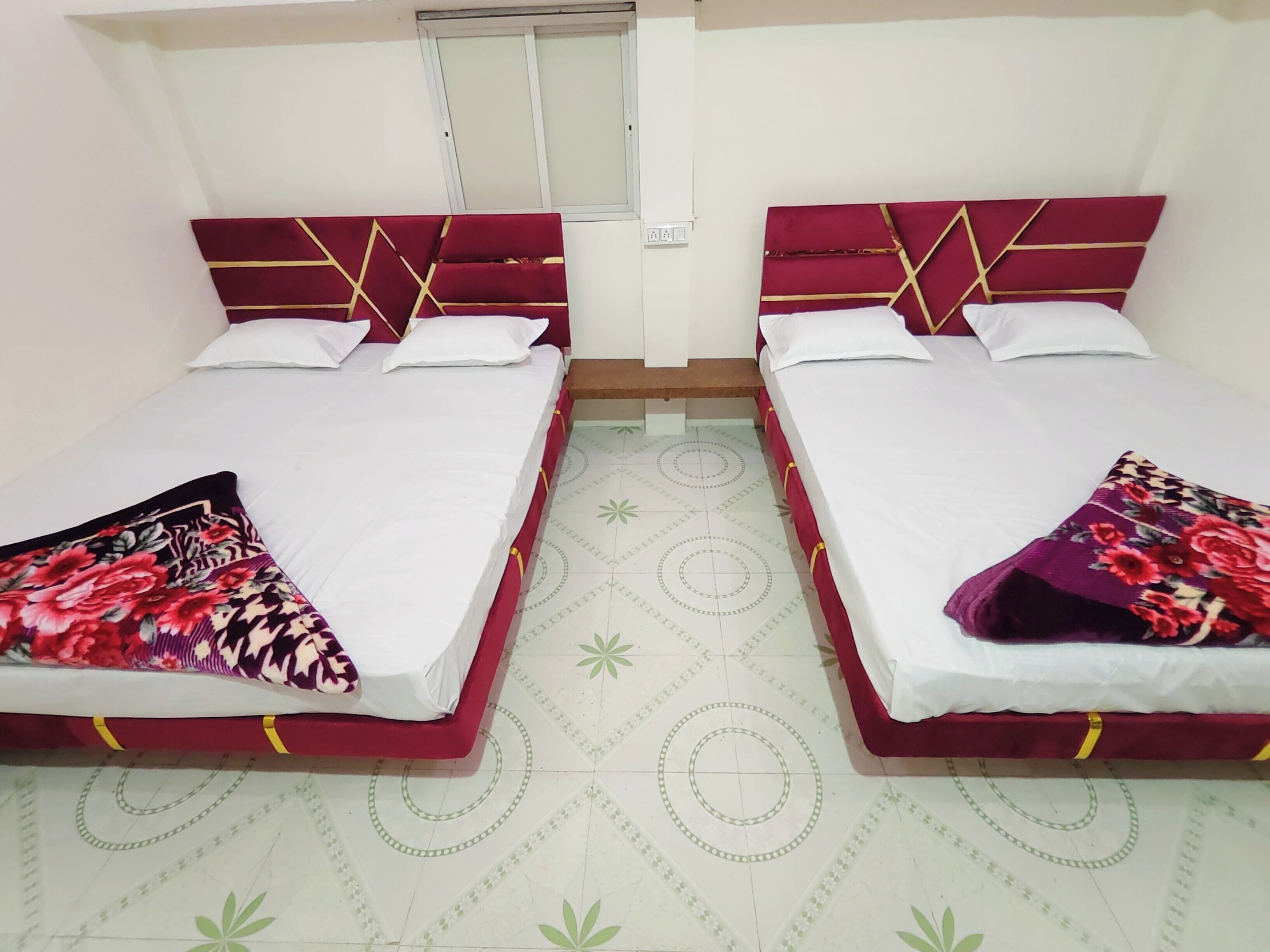 Ein Zimmer mit zwei Betten, jeweils mit rotem Kopfteil und weißer Bettwäsche.