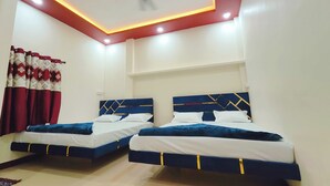 Une chambre avec deux lits, un ventilateur de plafond et un mur d’accent de couleur rouge.