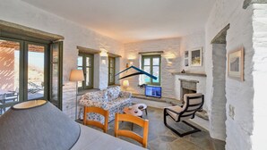 A cozy room with a stone fireplace, a sofa, and a dining table with chairs.