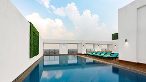 Ein Swimmingpool mit Liegestühlen und einer grünen Wand.