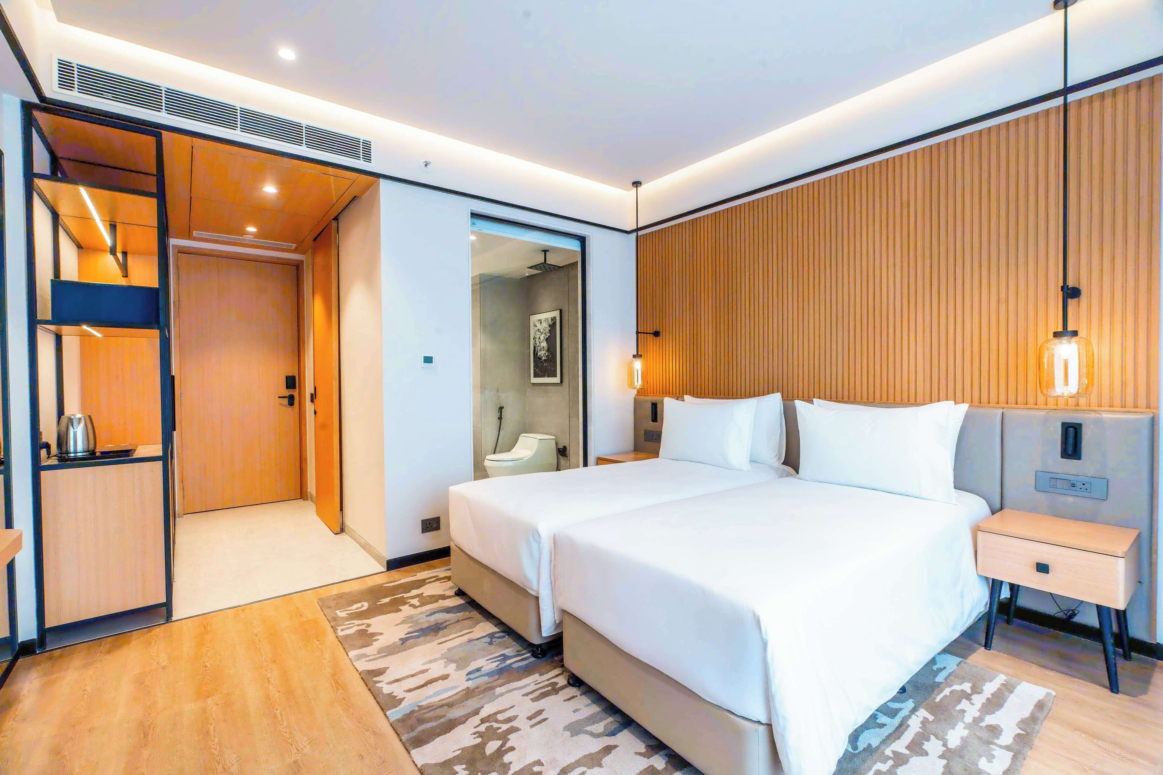 A modern hotel room with a large bed, bedside tables, a built-in wardrobe, and a shower area.