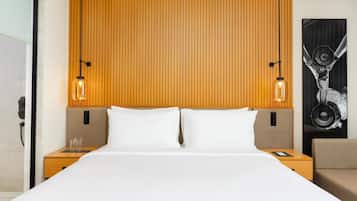 A hotel room with a wooden headboard, two bedside tables with lamps, a bed with white linens, and a large abstract painting on the wall.