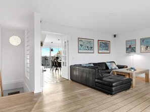Un salon moderne avec un canapé en cuir, un coin repas avec des chaises et des œuvres d’art accrochées aux murs.