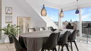 Un espace repas moderne avec une table ronde, des chaises noires et des luminaires suspendus.
