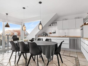 Une cuisine moderne avec un coin repas, de grandes fenêtres et une vue sur l’extérieur.