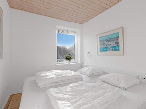 A bedroom with two beds, a window with a view of trees, and a painting on the wall. - 5 Star Holiday Home in Lokken (Lokken)
