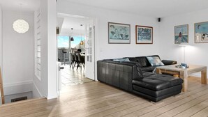 Un salon moderne avec un canapé en cuir noir, une table basse en bois et un coin repas comprenant des chaises et une table.