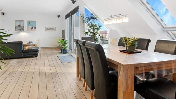 Un espace repas moderne avec une table en bois, des chaises noires et des plantes en pot.