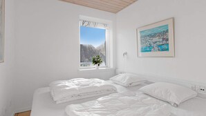 Une chambre avec deux lits, une fenêtre donnant sur des arbres et un tableau accroché au mur.