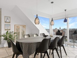 A modern dining area with a round table, black chairs, and pendant lighting. - 5 Star Holiday Home in Lokken (Lokken)