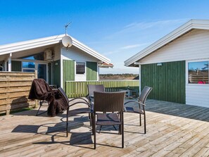 A wooden deck with outdoor furniture and a small building with a satellite dish.