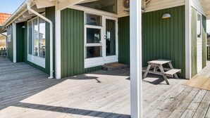 A covered outdoor area with a wooden deck, a small table, and a bench.