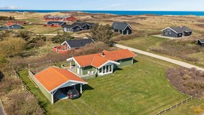 An aerial view of a residential area with houses, a clear sky, and a coastline in the background.