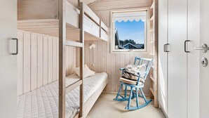 A compact room with bunk beds, a rocking chair, a window with a view, and a door with a key lock.