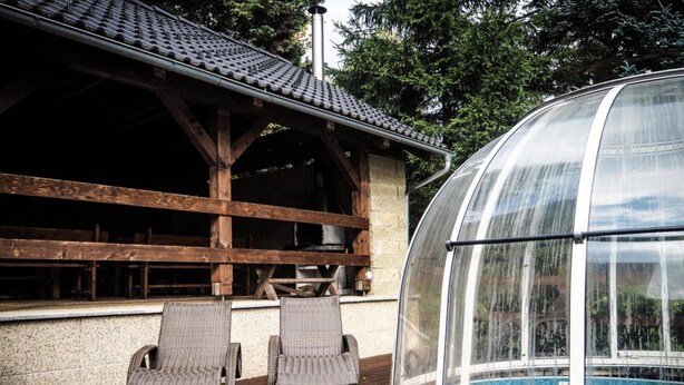 A covered outdoor area with a pool, two wicker chairs, and a wooden pergola. - Villa in Stare Hamry Near Ski Park Grun (Staré Hamry)