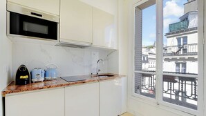 A kitchen with white cabinets, a microwave, a toaster, and a kettle on the counter. - Modern Apartment - 2bd/4p - Louvre/marais (Paris)
