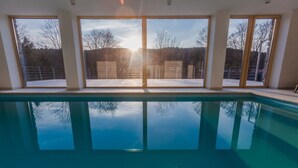 Ein Hallenbad mit großen Fenstern und Blick auf eine verschneite Landschaft.