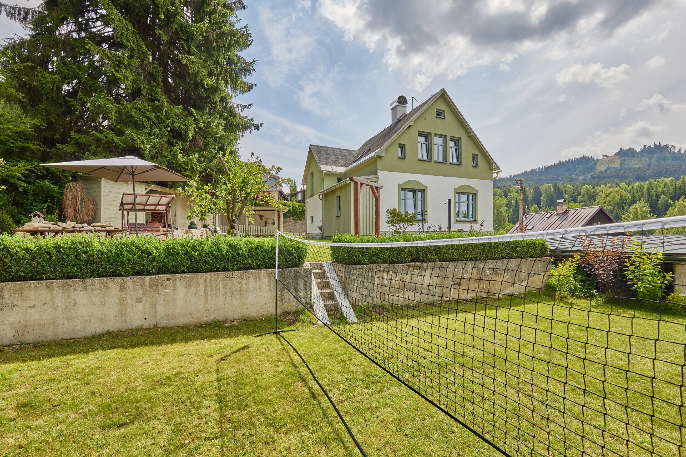 Ein Haus mit Tennisplatz, einer überdachten Sitzgelegenheit und einer Steinmauer.