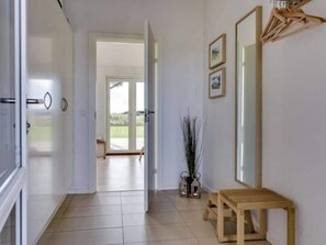 A hallway with a wooden bench, a mirror, and a door leading to a bright room. - 5 Star Holiday Home in Lokken (Lokken)