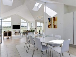 Un vaste espace dédié à la salle à manger, doté d’un haut plafond, de grandes fenêtres et d’un aménagement intérieur moderne.