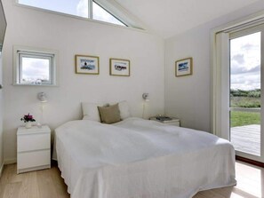 Une chambre à coucher avec un lit, des tables de chevet et des tableaux encadrés accrochés au mur.