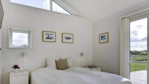 Une chambre avec un grand lit, une table de chevet, une commode et des tableaux encadrés accrochés au mur.