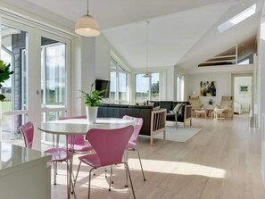 A modern kitchen with a dining area, large windows, and a view of the outdoors. - 5 Star Holiday Home in Lokken (Lokken)