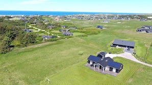 Un quartier résidentiel avec des maisons, un grand espace vert et une vue sur l’océan.