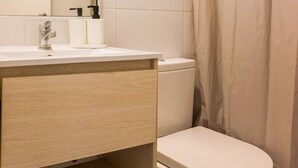 Une salle de bain équipée de toilettes, d’un lavabo, d’un miroir et d’un rideau de douche.