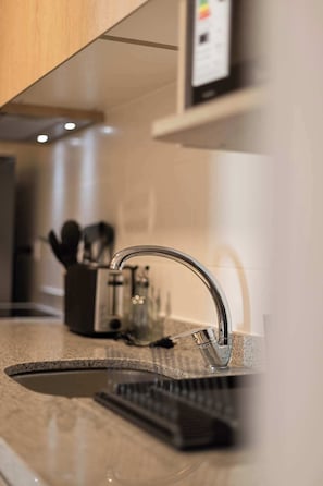 Una cocina moderna con un grifo de acero inoxidable, una encimera de granito y un juego de cuchillos.