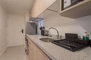 A modern kitchen with a stainless steel sink, a built-in oven, and a countertop with a dish rack.