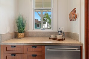 A kitchen with a window, a coffee maker, and a plant. - Hale Akea by Alekona Kauai: Charming 3br Cottage w AC, Ocean Views, Spa, large yard (Koloa)