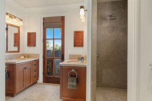 A bathroom with wooden cabinets, a sink, a mirror, and a shower. - Hale Akea by Alekona Kauai: Charming 3br Cottage w AC, Ocean Views, Spa, large yard (Koloa)