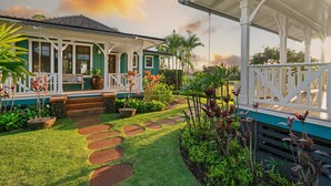 A house with a covered porch, a garden with stepping stones, and a pathway leading to the entrance.