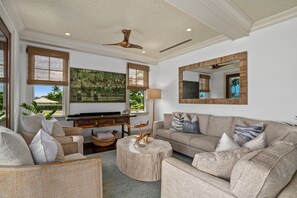 Ein geräumiges Wohnzimmer mit einer großen Couch, einem Couchtisch und einem Gemälde an der Wand.
