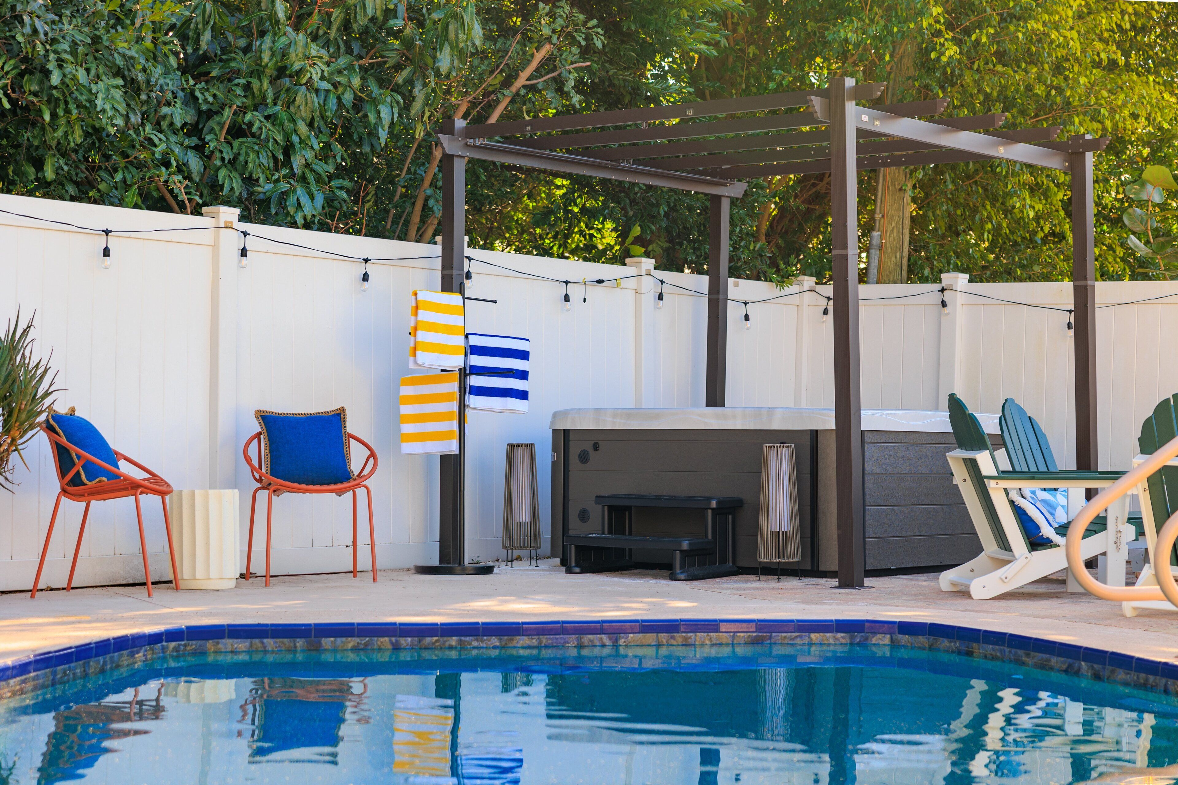 Ein Garten mit Schwimmbad, Gartenmöbeln, Grill und einer Pergola.