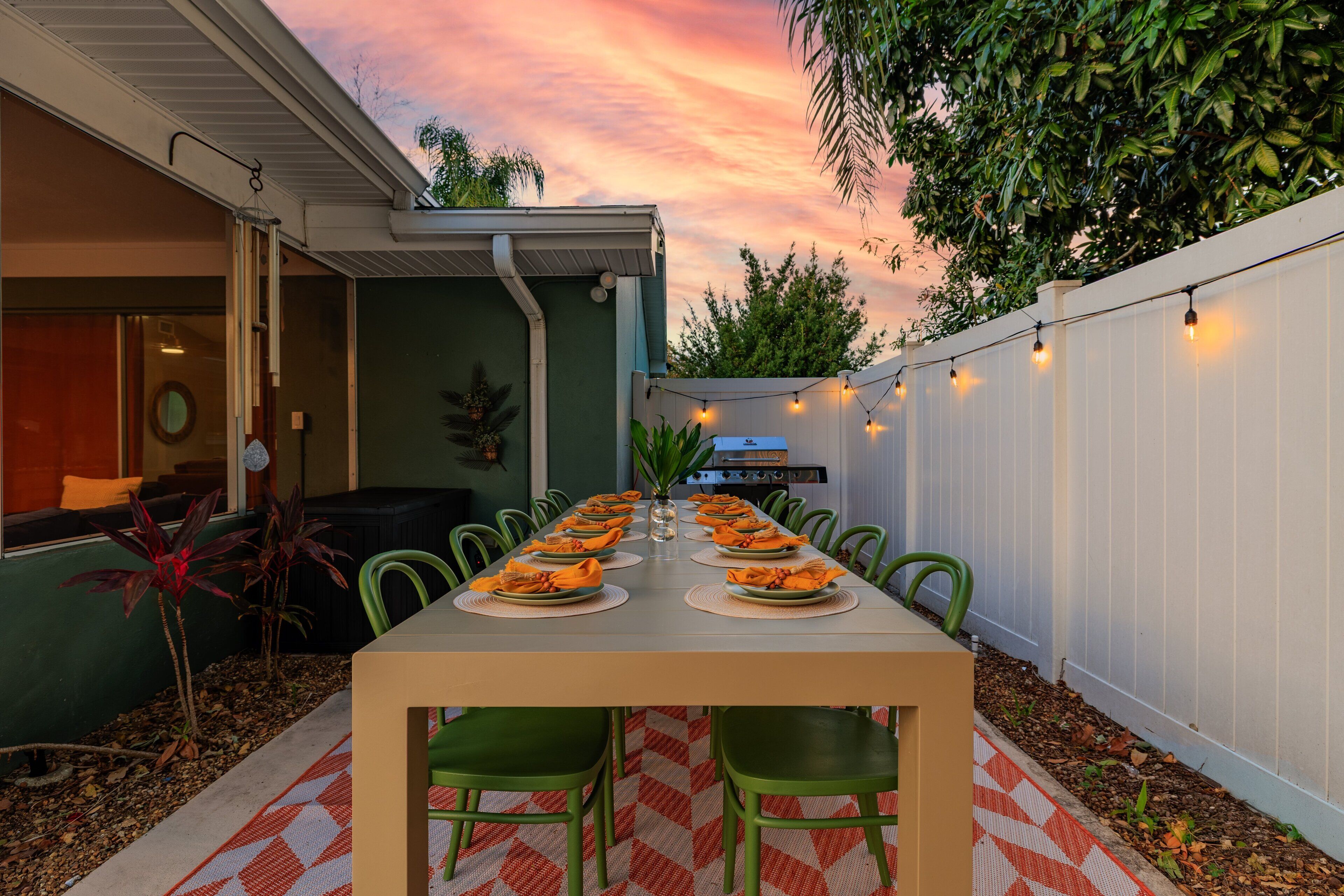 Une table à manger dressée pour un repas, avec des chaises, un centre de table décoratif et une guirlande lumineuse.