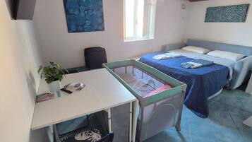 A room with a bed, a desk, a chair, a window, and a painting on the wall.
