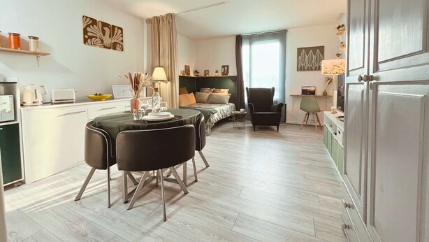 A modern apartment with a dining area, kitchen, and a bedroom.