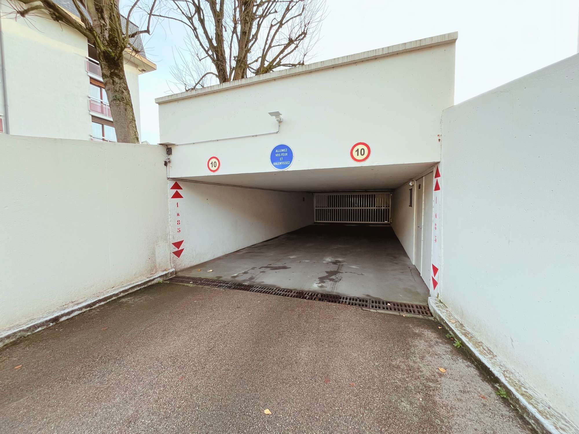 Un parking souterrain avec un sol en béton et des garde-corps métalliques.
