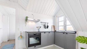 A modern kitchen with grey cabinets, a built-in oven, and a window providing natural light. - 5 Star Holiday Home in Hjorring (Hjørring)