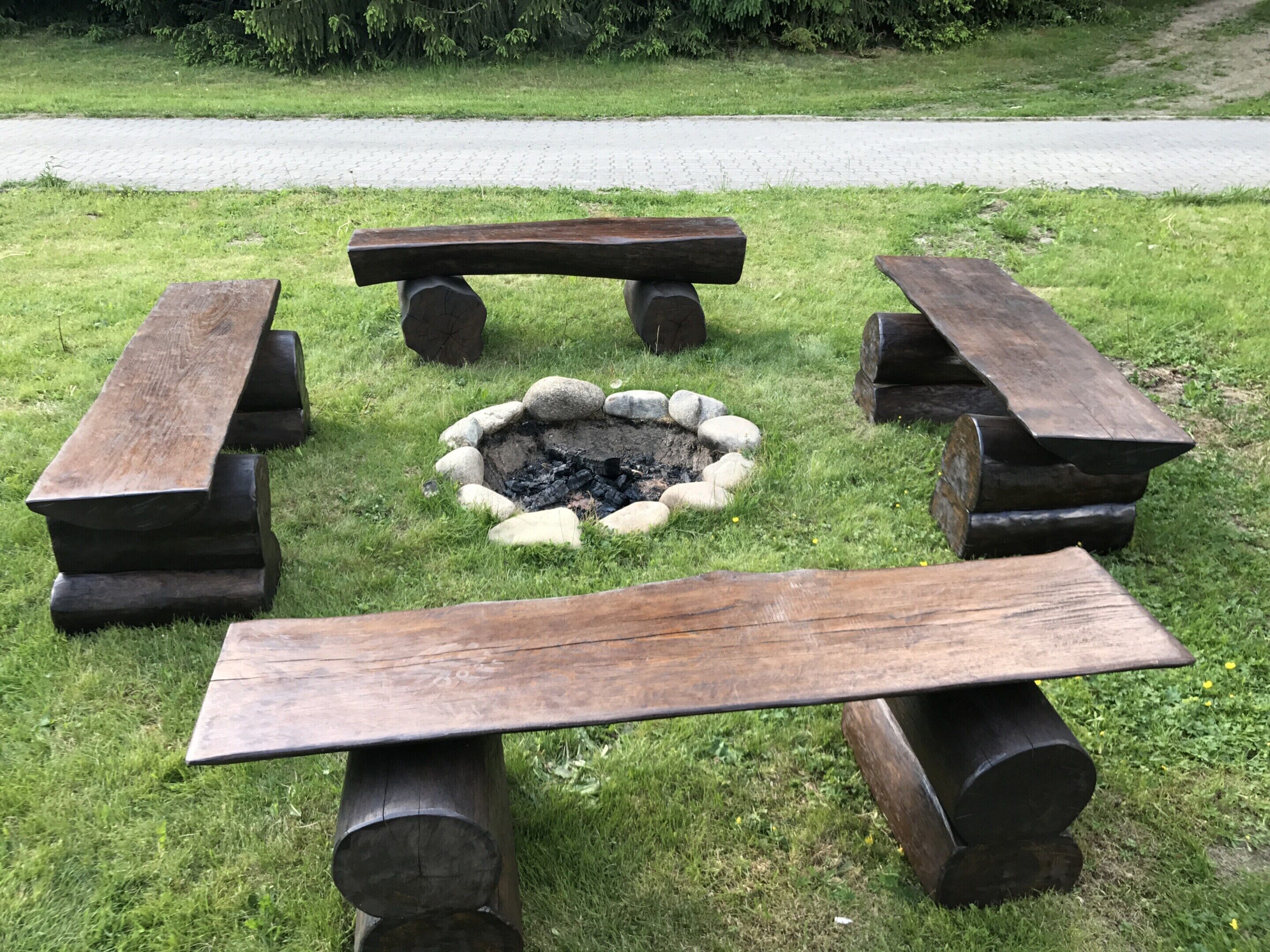 A fire pit surrounded by four wooden benches.